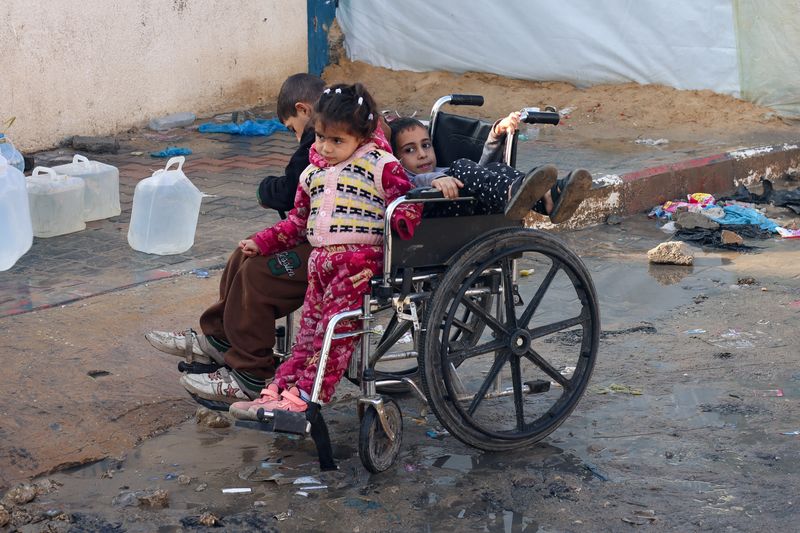 © Reuters. Niños palestinos sentados en una silla de ruedas mientras se dirigen a recoger agua, een Rafah, sur de la Franja de Gaza

Dic 31, 2023. REUTERS/Saleh Salem