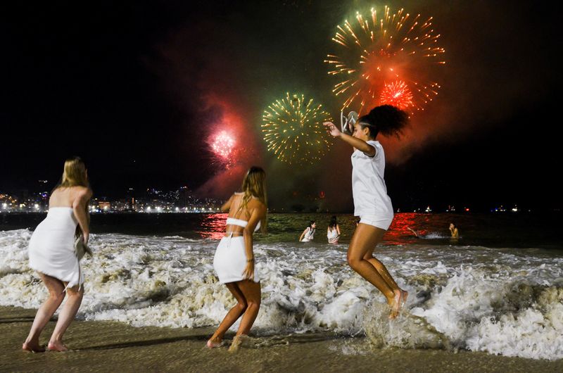 &copy; Reuters. Un grupo de personas celebra el Año Nuevo mientras estallan fuegos artificiales en el cielo de la playa de Copacabana en Río de Janeiro, Brasil. 1 de enero de 2024. REUTERS/Tita Barros