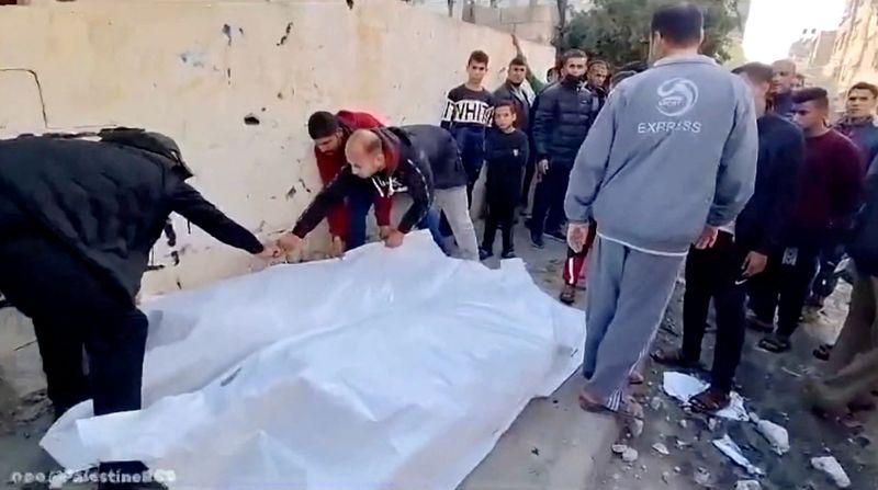 &copy; Reuters. Varias personas cubriendo cadáveres con una sábana blanca en una calle tras un ataque aéreo contra una casa en el campo de Maghazi, Deir al-Balah, en el centro de Gaza. 1 de enero de 2024. Media Luna Roja Palestina/vía REUTERS