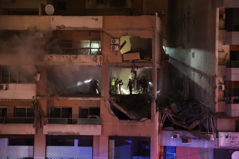 © Reuters. Un grupo de personas junto a un edificio dañado tras una explosión en Dahiyeh, suburbio de Beirut, Líbano. 2 de enero de 2024. REUTERS/Mohamed Azakir