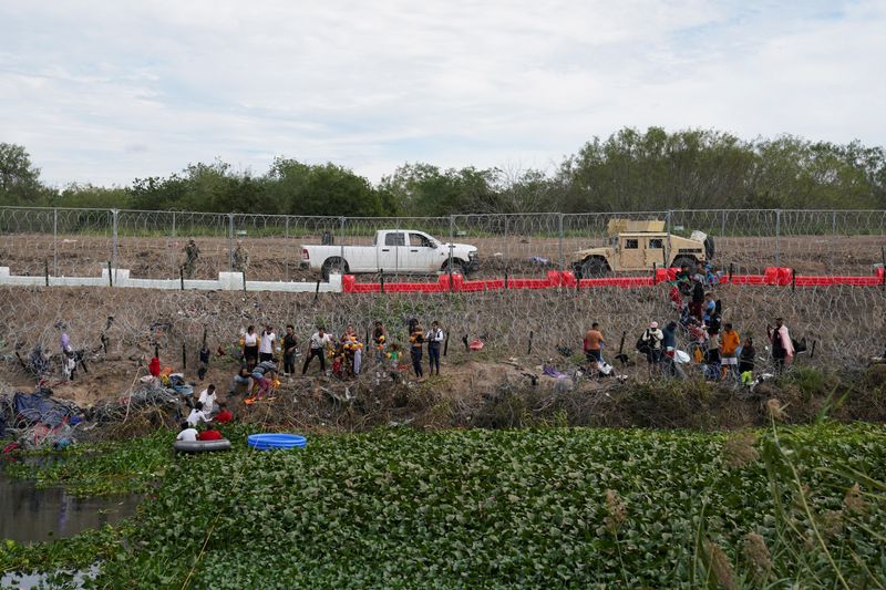 &copy; Reuters. FOTO DE ARCHIVO. La gente espera detrás de alambre de púas y barreras recién instaladas para presentarse ante las autoridades fronterizas de Estados Unidos, en Brownsville, Texas, visto desde Matamoros, México, el 29 de diciembre de 2023. REUTERS/Vero