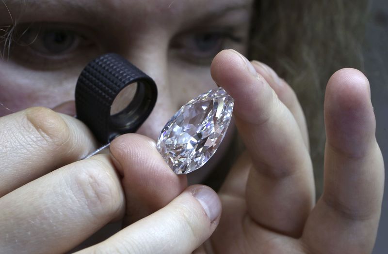 &copy; Reuters. Una dipendente ispeziona un diamante durante una dimostrazione presso l'impresa "Diamonds ALROSA", di proprietà della società Alrosa, a Mosca, 17 ottobre 2013. REUTERS/Sergei Karpukhin/ File Photo