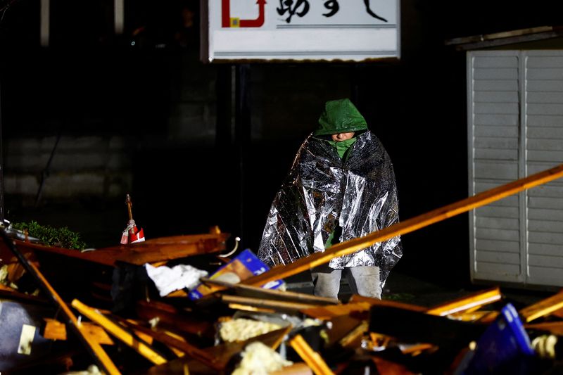 © Reuters. A person believed to be a family member of a victim waits as rescue workers remove a dead body from a collapsed building, following an earthquake in Wajima, Ishikawa prefecture, Japan, January 3, 2024. REUTERS/Kim Kyung-Hoon