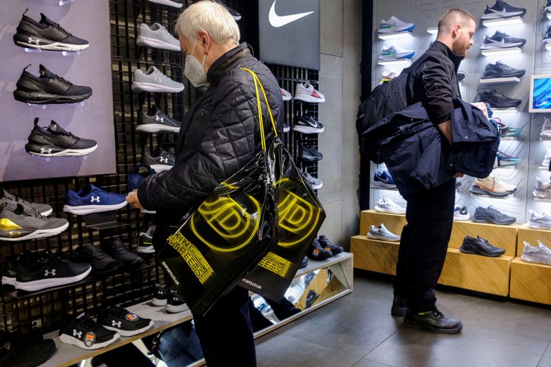&copy; Reuters. FILE PHOTO: A shopper carrying JD Sports bags looks at footwear at a JD Sports store in London, Britain. Picture taken November 17, 2021. REUTERS/May James/File Photo