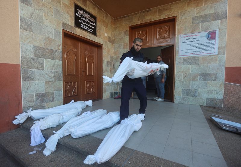 &copy; Reuters. شخص يحمل جثمان لفلسطيني قتل جراء الغارات الإسرائيلية علي قطاع غزة ليضعه بجوار جثامين أخري في مستشفي بخان يونس يوم الخميس. تصوير: أحمد زقوت - 