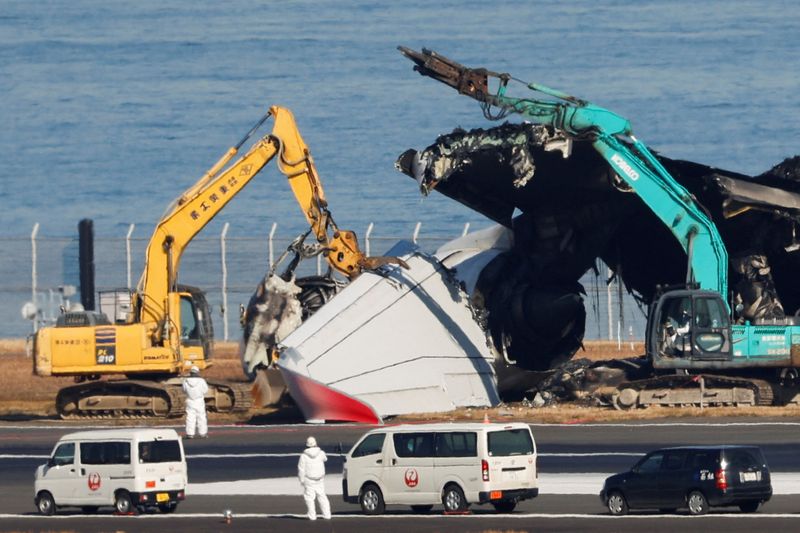 © Reuters. Officials try to remove the wreckage of a burnt Japan Airlines (JAL) Airbus A350 plane after a collision with a Japan Coast Guard aircraft at Haneda International Airport in Tokyo, Japan January 5, 2024.  REUTERS/Issei Kato