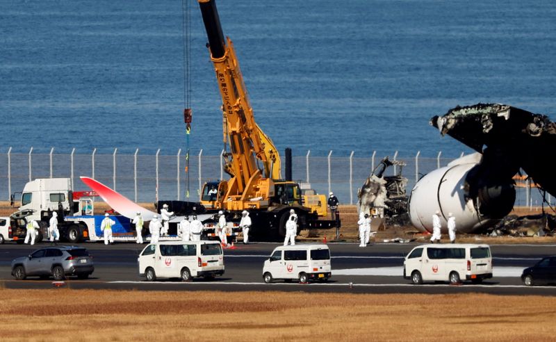 © Reuters. Officials remove the wreckage of a burnt Japan Airlines (JAL) Airbus A350 plane after a collision with a Japan Coast Guard aircraft at Haneda International Airport in Tokyo, Japan January 5, 2024. REUTERS/Issei Kato