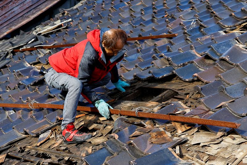 &copy; Reuters. Hiroshi Omukai cherche son ordinateur à travers le toit de son atelier de réparation automobile endommagé, à la suite d'un tremblement de terre, à Wajima, dans la préfecture d'Ishikawa, au Japon. /Photo prise le 5 janvier 2024/REUTERS/Kim Kyung-Hoon