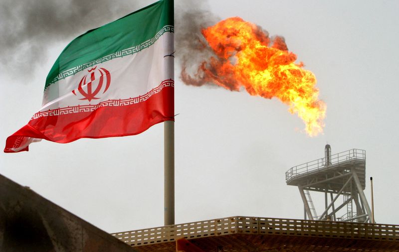 &copy; Reuters. FOTO DE ARCHIVO. Una llama de gas en una plataforma de producción de petróleo junto a una bandera iraní en el golfo Pérsico. 25 de julio de 2005. REUTERS/Raheb Homavandi