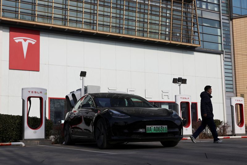 © Reuters. A man walks near a Tesla car at a charging station outside a store of the electric vehicle (EV) maker in Beijing, China January 4, 2024. REUTERS/Florence Lo