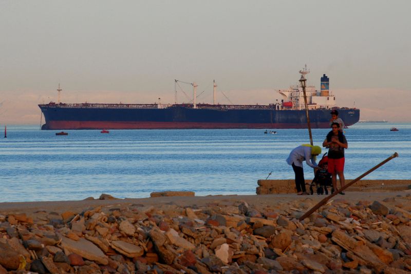 © Reuters. FILE PHOTO: People walk on the beach as a container ship crosses the Gulf of Suez towards the Red Sea before entering the Suez Canal, in El Ain El Sokhna in Suez, east of Cairo, Egypt April 24, 2017. Picture taken April 24, 2017. REUTERS/Amr Abdallah Dalsh/File Photo