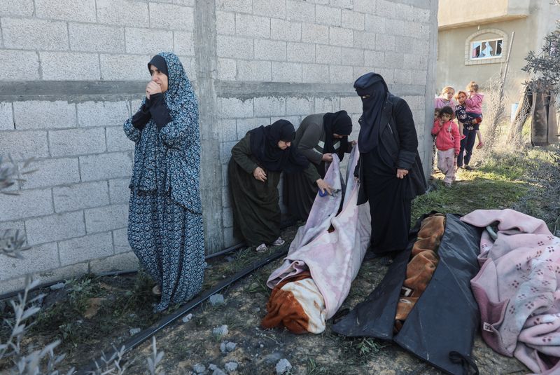 &copy; Reuters. مشيعون يقفون بجوار جثث أقاربهم في موقع غارة إسرائيلية في رفح بجنوب قطاع غزة يوم الأحد. تصوير: عرفات بربخ - رويترز.
