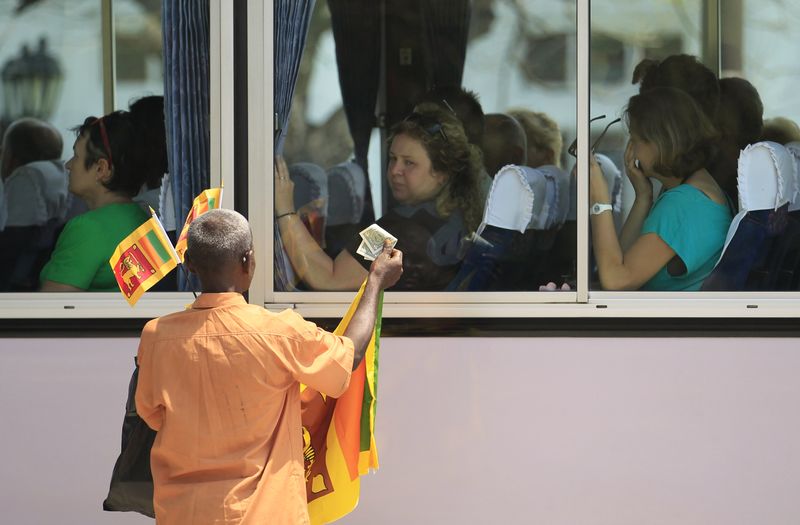 &copy; Reuters. A vendor shows a U.S. dollar note as he tries to sell Sri Lanka's national flags to tourists seated inside a bus in Colombo March 14, 2014. REUTERS/Dinuka Liyanawatte/File Photo