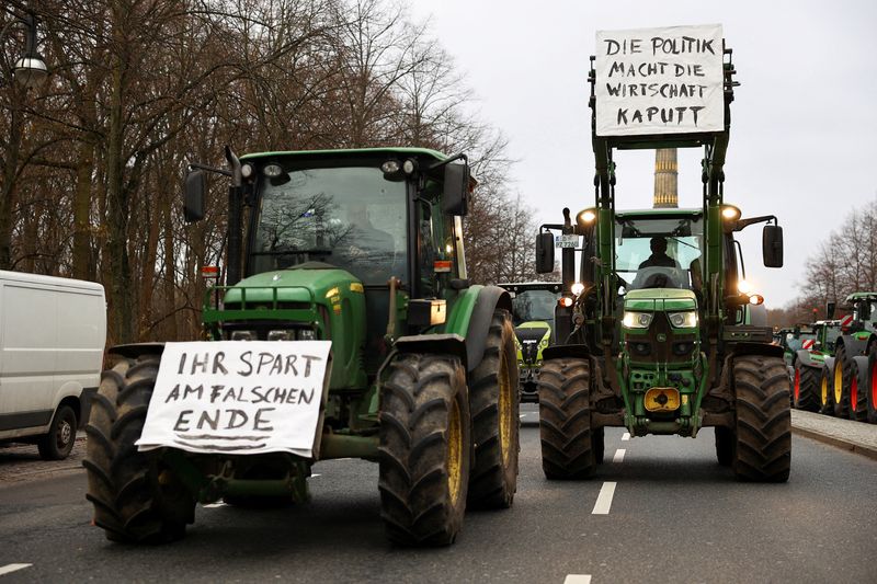 &copy; Reuters. FILE PHOTO: German farmers in tractors take part in a protest against the cut of vehicle tax subsidies, as signs are displayed on the front of their tractors that read "You're saving at the wrong end" and "Politics is breaking the economy", in Berlin, Ger