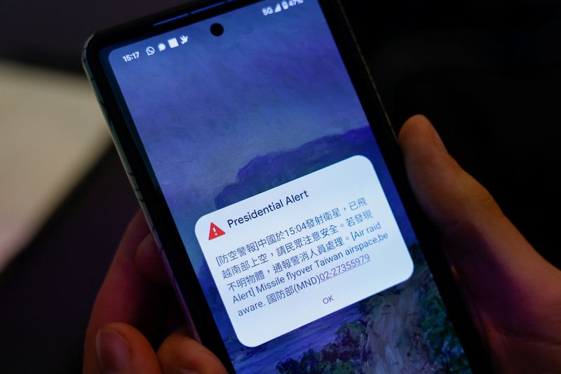 &copy; Reuters. Una persona que asiste a una conferencia de prensa del Ministerio de Asuntos Exteriores sostiene un teléfono que muestra la alerta de ataque aéreo sobre un satélite chino que había sobrevolado el espacio aéreo del sur de Taiwán, en Taipéi, Taiwán.