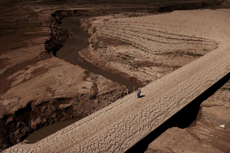 &copy; Reuters. Un uomo cammina sul terreno pieno di crepe del serbatoio di Baells, mentre le riserve di acqua potabile sono scese al livello più basso dal 1990 a causa dell'estrema siccità in Catalogna, nel villaggio di Cersc, nella regione di Bergueda, Spagna, 14 mar