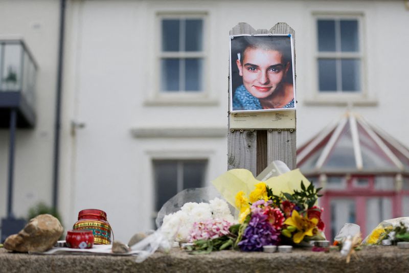 &copy; Reuters. A picture of late singer Sinead O'Connor, who died at the age of 56, known for her chart-topping hit "Nothing Compares 2 U", is placed around floral tributes outside her former Irish home, in the seaside town of Bray in County Wicklow, Ireland, July 27, 2