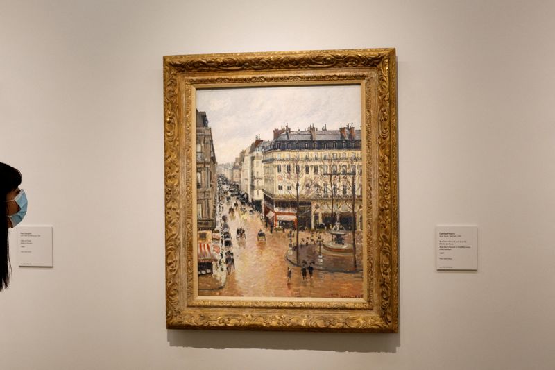 © Reuters. FILE PHOTO: A visitor leans to look at Camille Pissarro's 