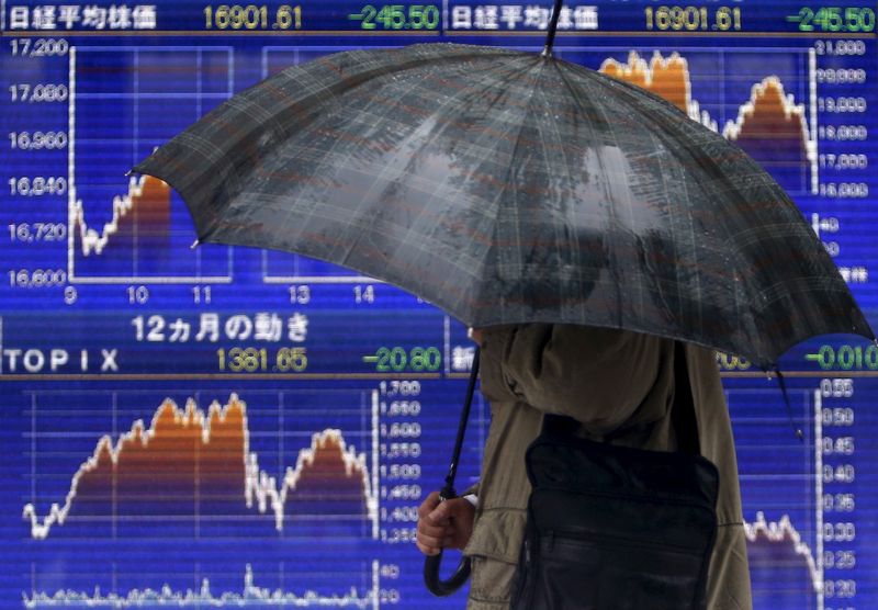 &copy; Reuters. A pedestrian holding an umbrella walks past an electronic board showing the graphs of the recent fluctuations of Japan's Nikkei average outside a brokerage in Tokyo, Japan, January 18, 2016. REUTERS/Yuya Shino/File Photo