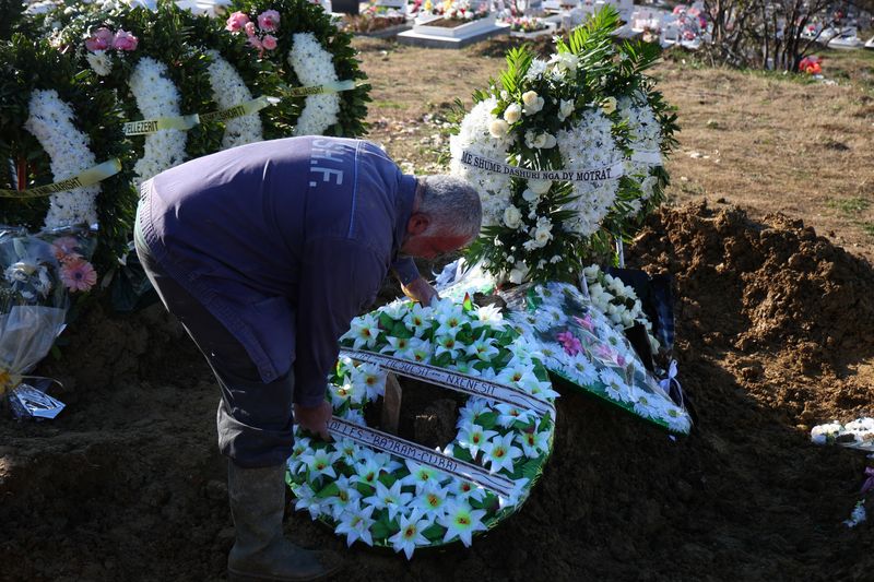 &copy; Reuters. A man arranges a wreath of flowers as family and friends take part in the funeral of Leonard Farruku, who died in December on the Bibby Stockholm accommodation barge in the United Kingdom, in Tirana, Albania, January 10, 2024. Farruku's body was brought h