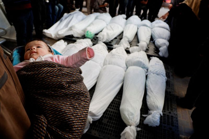 &copy; Reuters. طفلة فلسطينية ناجية من غارة إسرائيلية بيد والدها الذي يقف بجوار جثامين أقاربه الذين قتلوا في الغارة في صورة التقطت في رفح جنوب قطاع غزة يوم 