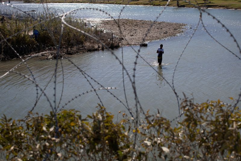 © Reuters. A man crosses the Rio Grande River from Mexico to collect clothing and other items left on the Texas banks of Shelby Park at the U.S.-Mexico border in Eagle Pass, Texas, U.S., January 12, 2024.     REUTERS/Kaylee Greenlee Beal 
