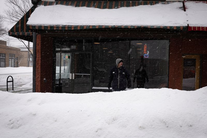 &copy; Reuters. FILE PHOTO: A man stands outside a coffee shop after a blizzard left several inches of snow, in downtown Des Moines, Iowa, U.S., January 13, 2024. REUTERS/Marco Bello/File Photo
