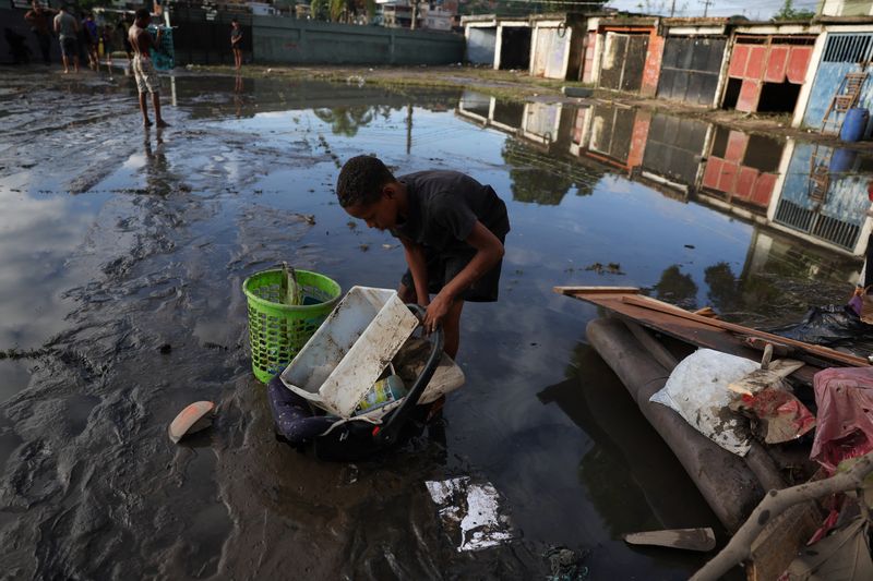 © Reuters. Criança recolhe pertences em área inundada no complexo de favelas da Pedreira após as fortes chuvas que atingiram o Rio de Janeiro
14/01/2024 REUTERS/Pilar Olivares