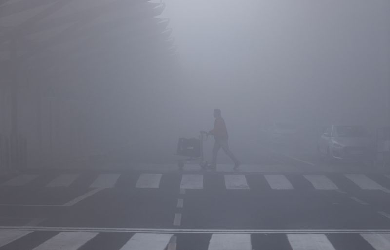 &copy; Reuters. FOTO DE ARCHIVO: Un hombre camina con su carrito de equipaje en medio de una densa niebla en el Aeropuerto Internacional Indira Gandhi en Nueva Delhi, India. 27 de diciembre de 2023. REUTERSAnushree Fadnavis/Archivo