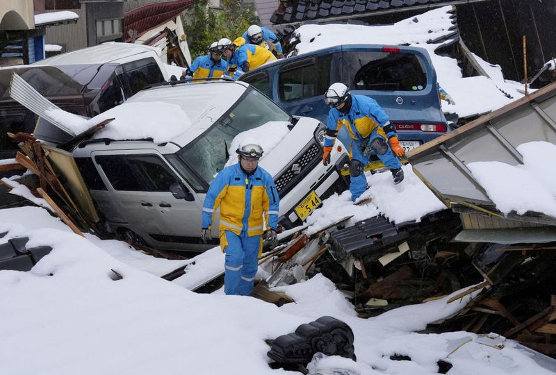&copy; Reuters. أفراد شرطة يبحثون عن ناجين في منطقة سكنية مغطاة بالثلوج دمرها تسونامي في أعقاب زلزال في محافظة إيشيكاوا باليابان بتاريخ التاسع من يناير كان