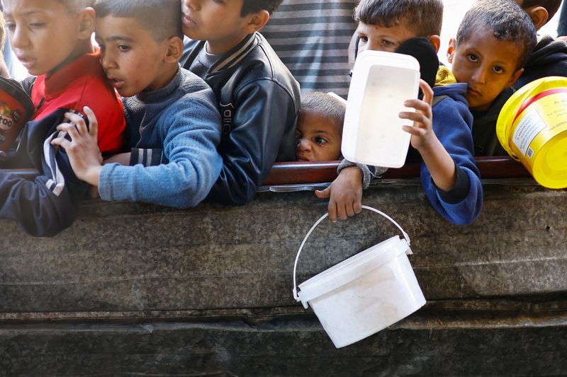 &copy; Reuters. Niños palestinos esperan para recibir alimentos de una cocina de caridad en medio de la escasez, en Rafah en el sur de la Franja de Gaza. 16 de enero de 2024. REUTERS/Ibraheem Abu Mustafa