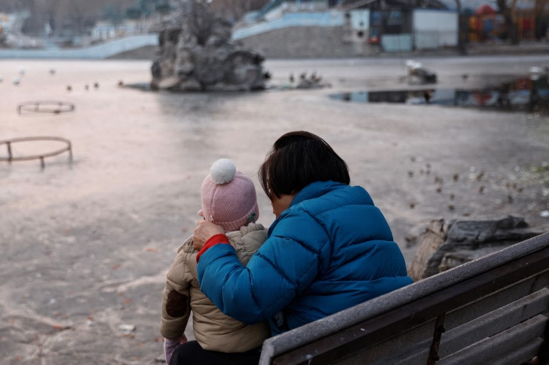 &copy; Reuters. Une femme et un enfant assis dans un parc à Pékin. /Photo prise le 12 janvier 2024/REUTERS/Tingshu Wang