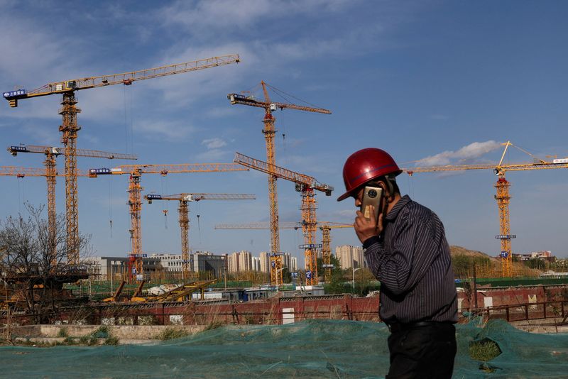 © Reuters. FILE PHOTO: A worker speaking on his phone walks past a construction site in Beijing, China April 14, 2022. REUTERS/Tingshu Wang/File Photo