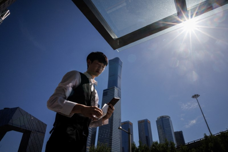 &copy; Reuters. A man walks in front of the skyline of the Central Business district in Beijing, China, July 14, 2022. REUTERS/Thomas Peter/File Photo