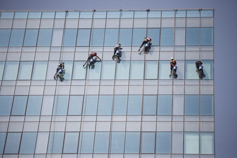 &copy; Reuters. FILE PHOTO: Workers clean the glass of an office building at the Gujarat International Finance Tec-City (GIFT) at Gandhinagar, India, December 8, 2023.REUTERS/Amit Dave/File Photo