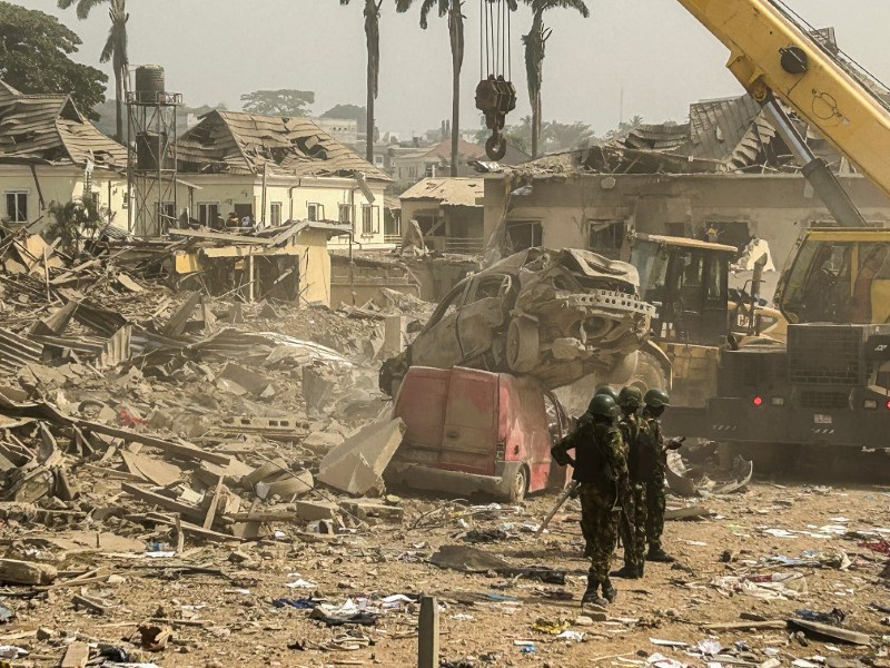 &copy; Reuters. عناصر من قوات الأمن النيجيرية تقف بالقرب من سيارات ومنازل مدمرة بينما تقوم جرافات بإزالة الأنقاض جراء انفجار مواد متفجرة بمنزل في أحد أحياء