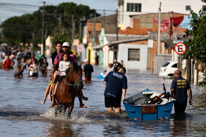 &copy; Reuters. Pessoas usam cavalo para atravessar rua alagada em Eldorado do Sul, no Rio de Grande do Sul
20/11/2023
REUTERS/Diego Vara