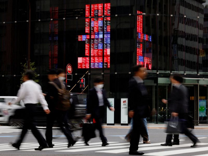 &copy; Reuters. FILE PHOTO: Pedestrians walk past an electronic board displaying various companies' share prices, at a business district in Tokyo, Japan, October 31, 2023. REUTERS/Kim Kyung-Hoon