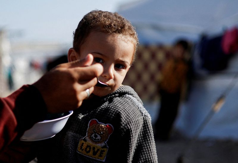 &copy; Reuters. Un niño palestino desplazado, que huyó de sus casas debido a los ataques israelíes, recibe alimentos en un campamento de tiendas de campaña, en medio del conflicto en curso entre Israel y el grupo islamista palestino Hamás, en Ráfah, en el sur de la