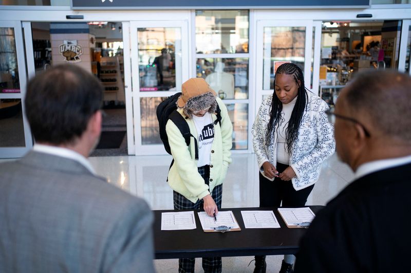 © Reuters. Dr. Benjamin Chavis Jr., national co-chair of No Labels, and Tyler Cymet, No Labels Maryland state co-chair, look on as a volunteer from No Labels, a third-party political group, collects signatures at the University of Maryland, Baltimore County, to gather support ahead of the 2024 U.S. presidential election, in Baltimore, Maryland, U.S., December 14, 2023. REUTERS/Bonnie Cash