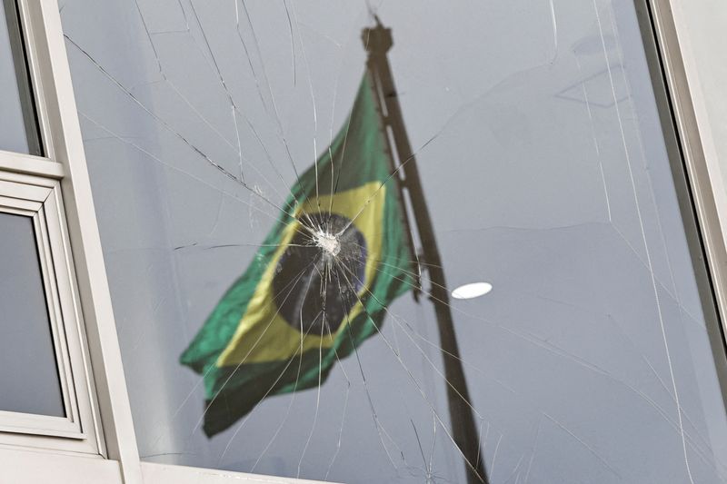 &copy; Reuters. Brazil's flag is reflected on a broken window, after the supporters of Brazil's former President Jair Bolsonaro participated in an anti-democratic riot at Planalto Palace, in Brasilia, Brazil, January 9, 2023. REUTERS/Ueslei Marcelino/ File Photo
