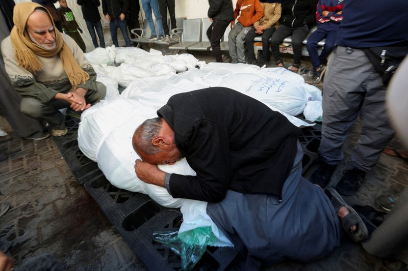 &copy; Reuters. أشخاص يبكون بجوار جثامين فلسطينيين قتلوا جراء غارة إسرائيلية في رفح جنوب قطاع غزة يوم الخميس. تصوير: إبراهيم أبو مصطفى - رويترز.

