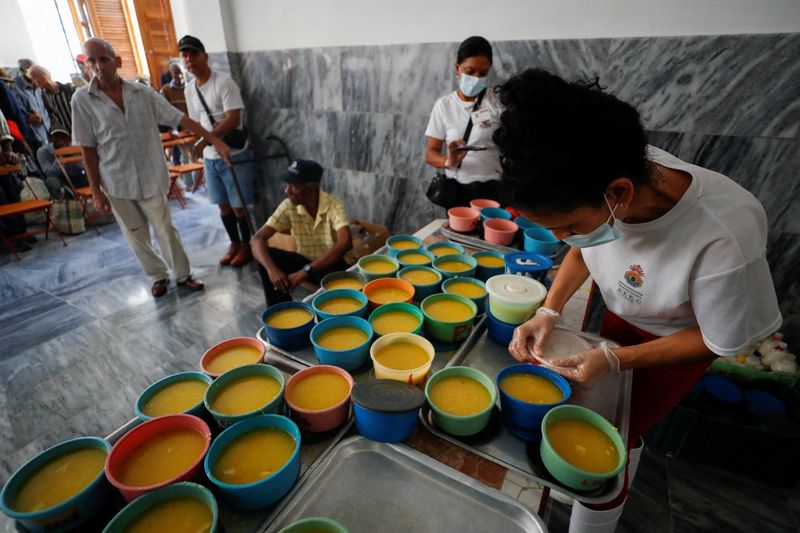 © Reuters. Un ayudante llena recipientes con comida para distribuir entre las personas necesitadas en un comedor social dirigido por el grupo religioso Quisicuaba que atiende a un número creciente de cubanos que luchan por llegar a fin de mes en medio de la crisis económica, en La Habana, Cuba 15 de enero 2024. REUTERS/Yander Zamora