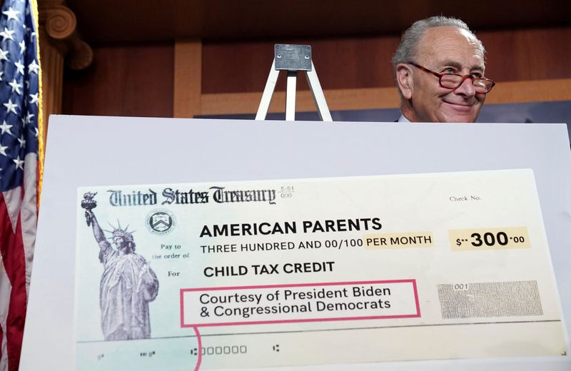 © Reuters. FILE PHOTO: U.S. Senate Majority Leader Chuck Schumer smiles from behind a mock U.S. Treasury check as he holds a press conference on the expanded Child Tax Credit payments at the U.S. Capitol in Washington, U.S., July 15, 2021. REUTERS/Kevin Lamarque/File Photo