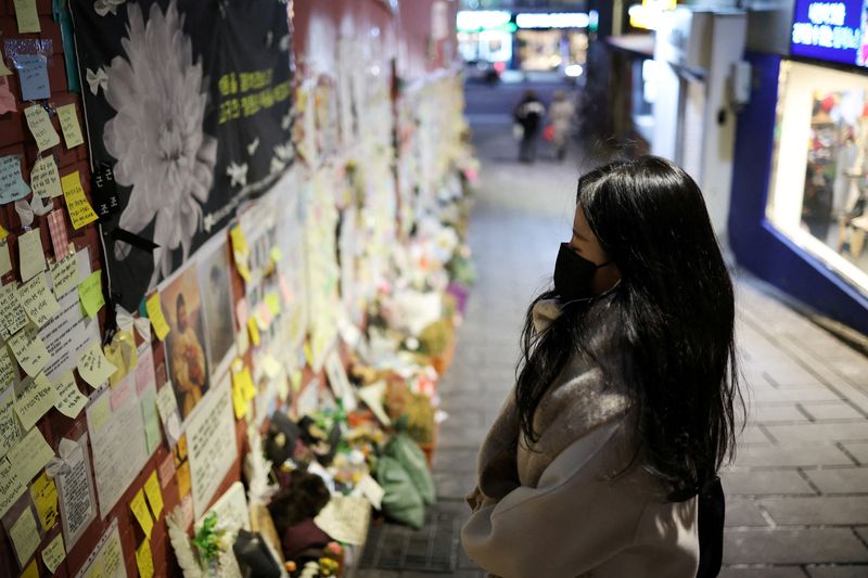 &copy; Reuters. FILE PHOTO: A woman prays while reading condolences messages attached to the wall of a narrow alley of Itaewon where the deadly Halloween crush that killed more than 150 in October happened, in Seoul, South Korea, December 18, 2022.  REUTERS/Kim Hong-Ji/F