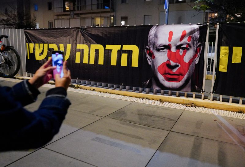 &copy; Reuters. A person takes a picture of a banner, during a protest against Israeli Prime Minister Benjamin Netanyahu's government in Tel Aviv, Israel, January 20, 2024. REUTERS/Alexandre Meneghini
