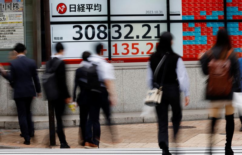 &copy; Reuters. FILE PHOTO: Pedestrians walk past an electronic board displaying Nikkei share average, outside a brokerage in Tokyo, Japan, October 31, 2023. REUTERS/Kim Kyung-Hoon/File Photo