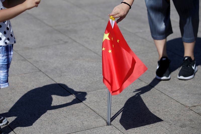 &copy; Reuters. FILE PHOTO: A mother holds Chinese flags as she helps her son take a picture on Tiananmen Square, in Beijing, China August 27, 2019. REUTERS/Jason Lee