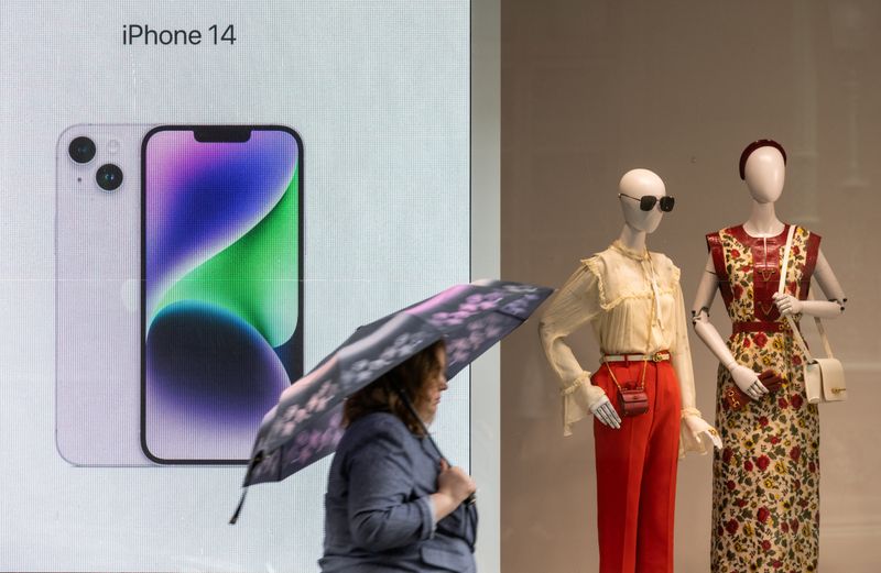 &copy; Reuters. FILE PHOTO: A woman with an umbrella walks past a display advertising Apple iPhone 14 during rainy weather in Moscow, Russia May 25, 2023. REUTERS/Maxim Shemetov/File Photo