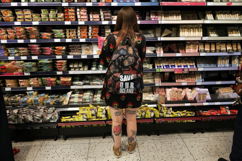 &copy; Reuters. FILE PHOTO: A person wearing a backpack with the slogan "SAVE OUR OCEANS", looks at food goods in a shop as UK inflation heads towards 10% in London, Britain, June 16, 2022. REUTERS/Kevin Coombs/File Photo